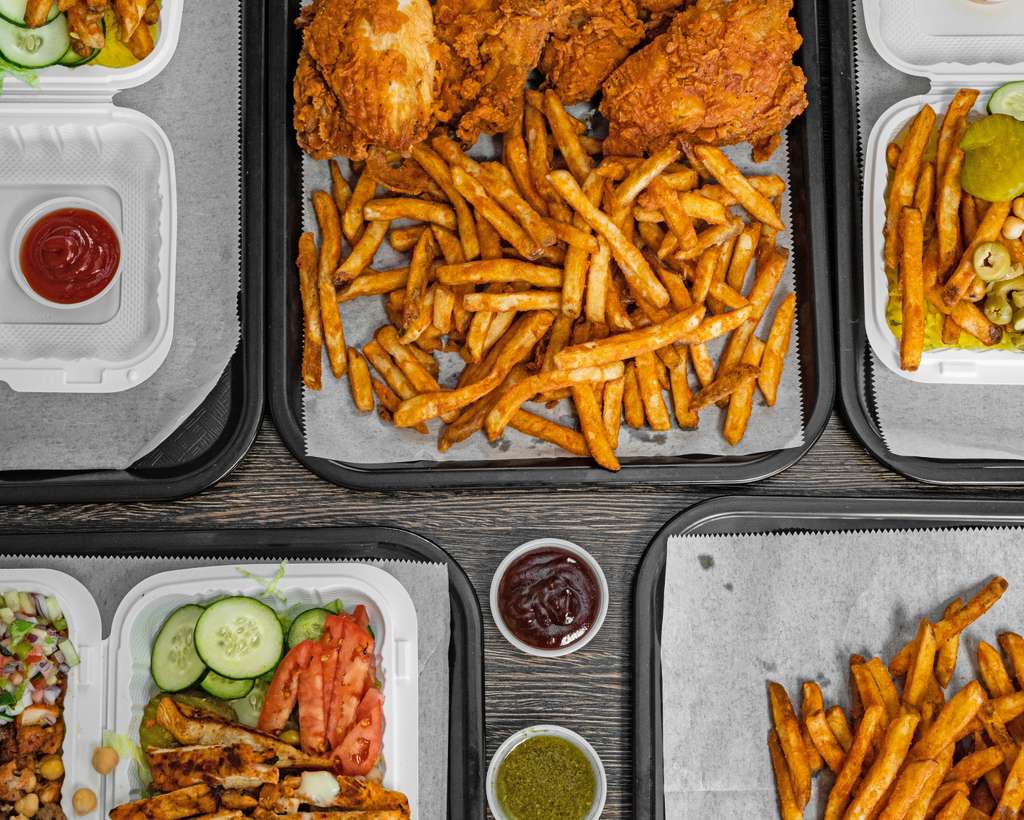 Overhead spread of fried chicken, fries, salad and dipping sauces